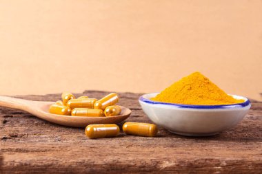 zerdeçal tozu, kapsül ve kökleri curcumin ahşap plaka üzerinde