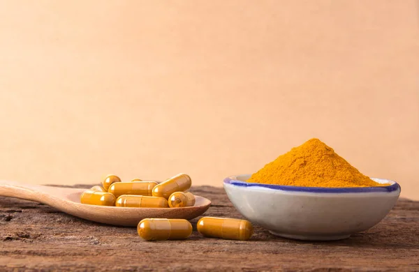 Kurkuma-Pulver, Kapsel und Curcumin-Wurzeln auf Holzteller — Stockfoto