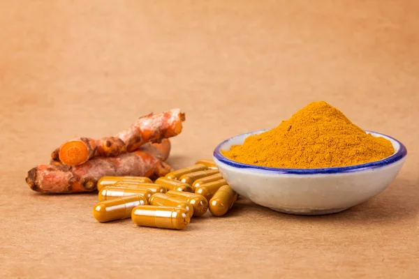 Kurkuma-Pulver, Kapsel und Curcumin-Wurzeln auf Holzteller — Stockfoto