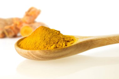 Beyaz zemin üzerine tahta kaşık kuru zerdeçal tozu kadar kapatın