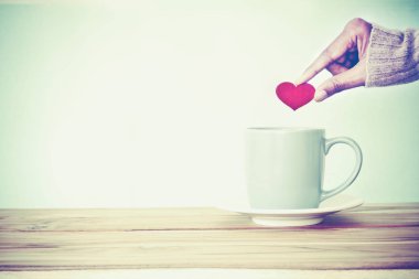 bir kahve fincanı kupa woode koymak kırmızı kalp şekli tutan el