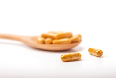 Beyaz zemin üzerine kaşık kapsüle zerdeçal kapatın