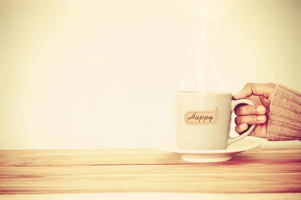 Ruka držící šálek kávy hrnek s šťastné slovo tag — Stock fotografie