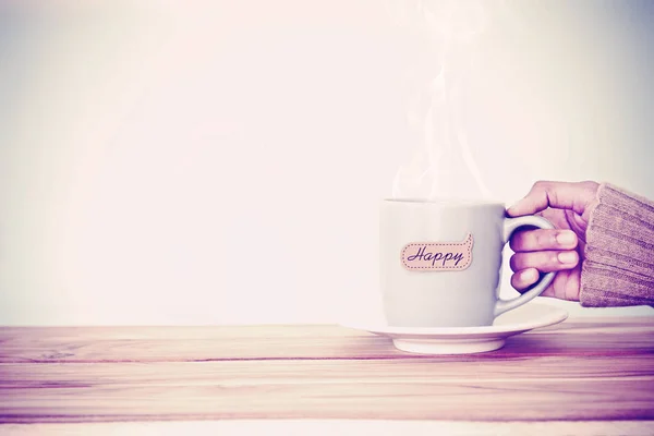 Ruka držící šálek kávy hrnek s šťastné slovo tag — Stock fotografie