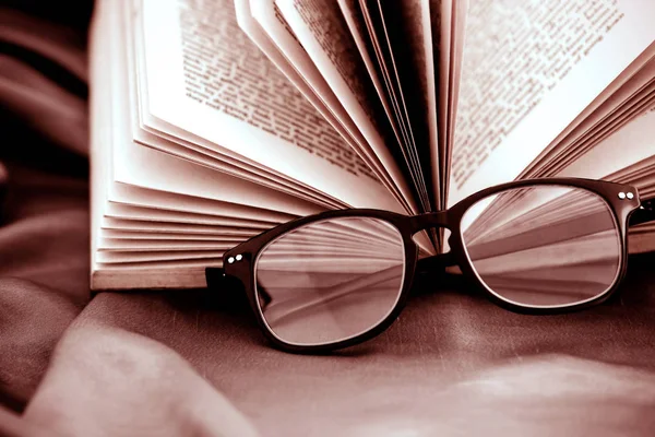 खोले गए किताब के साथ चश्मे पढ़ने का चयनात्मक ध्यान — स्टॉक फ़ोटो, इमेज
