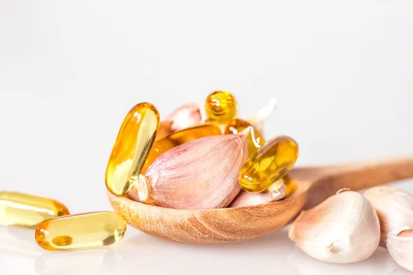  Garlic oil capsule gel supplement in a wooden spoon 