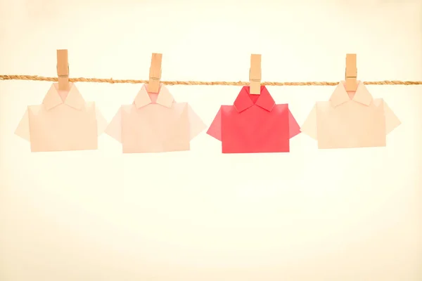 One Red among white origami shirt paper hanging  on rope , uniqu — Stock Photo, Image