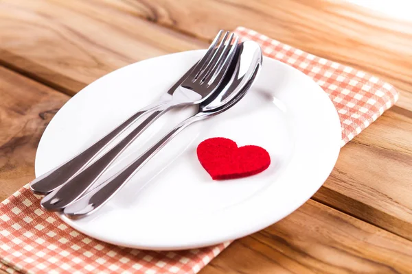 Forma de corazón rojo con plato blanco vacío con tenedor y cuchara en wo — Foto de Stock