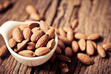 Peeled badem fındık üzerinde ahşap backg küçük beyaz Kupası kapatın