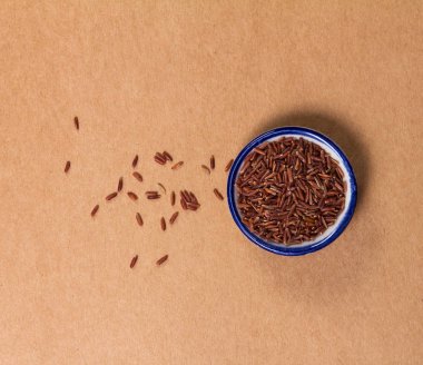 Kupası doğal kahverengi kağıt arka plan üzerinde kırmızı taneli pirinç