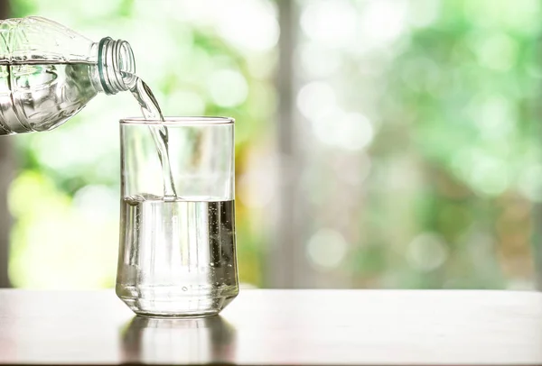 Наливаючи очищену свіжу питну воду з пляшки на столі — стокове фото