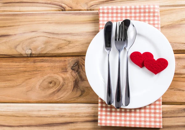 red heart shape with White empty plate with fork and spoon on wo