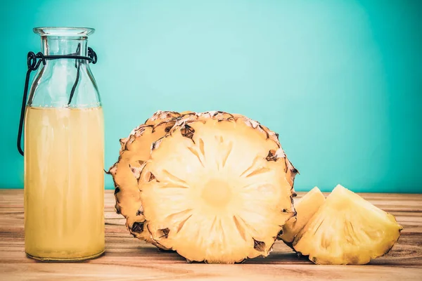 The Bottles of pineapple juice with sliced pineapple fruit on wo — Stock Photo, Image