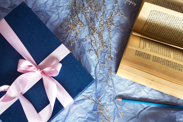 Dark blue gift box with  ribbon decoration with book and flower