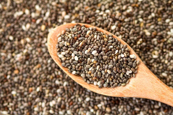 Close up sementes de chia em colher de madeira no fundo de sementes de chia — Fotografia de Stock