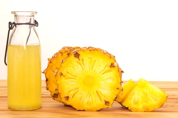 The Bottles of pineapple juice with sliced pineapple fruit on wo — Stock Photo, Image
