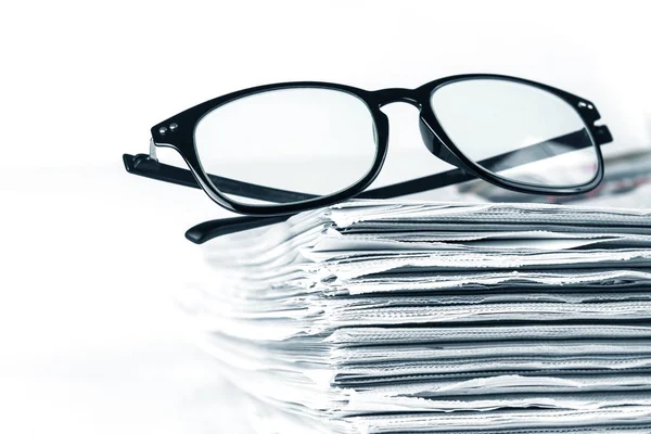 Selective focus on reading eyeglasses with stacking of newspaper — Stock Photo, Image