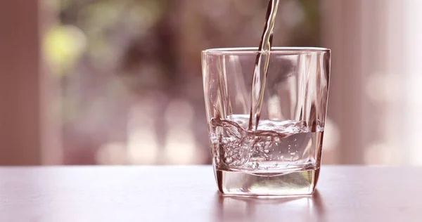 Chiudere versando acqua fresca purificata dalla bottiglia su un — Foto Stock