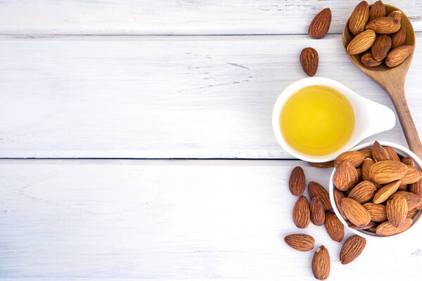 Close up almond oil in the bottle and almond seed in white cup f