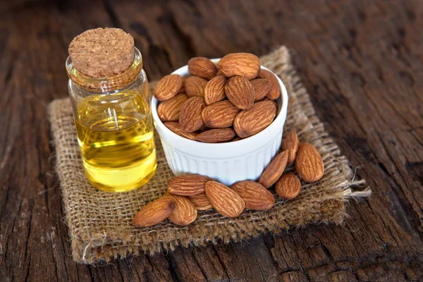 Close up almond oil in the bottle and almond seed in white cup f