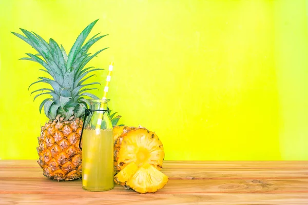 Botellas de jugo de piña con una fruta de piña en rodajas sobre madera —  Fotos de Stock