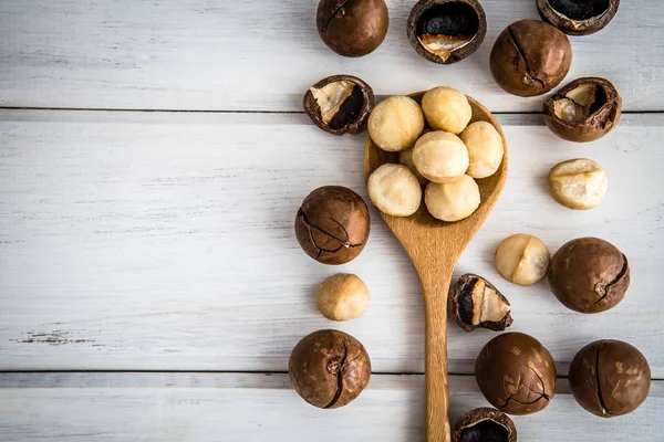 Beyaz ahşap arka plan, superfood Macadamia fındık kadar kapatın 