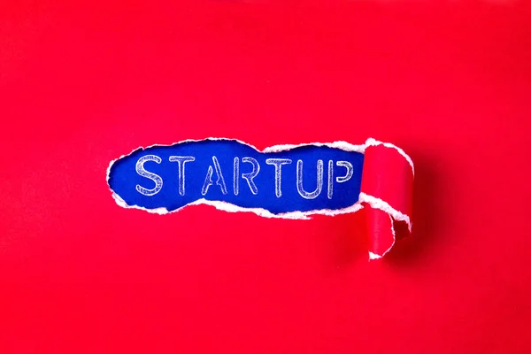 El papel rojo desgarrado y el texto STARTUP con un fondo de papel azul — Foto de Stock