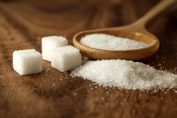 Close up  sugar cubes and cane in wooden spoon on the table — Stock Photo, Image