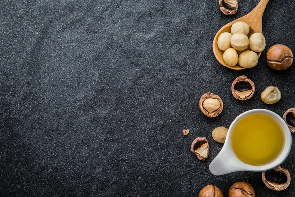 Макадамия ореховое масло и орех макадамии на черном санто — стоковое фото