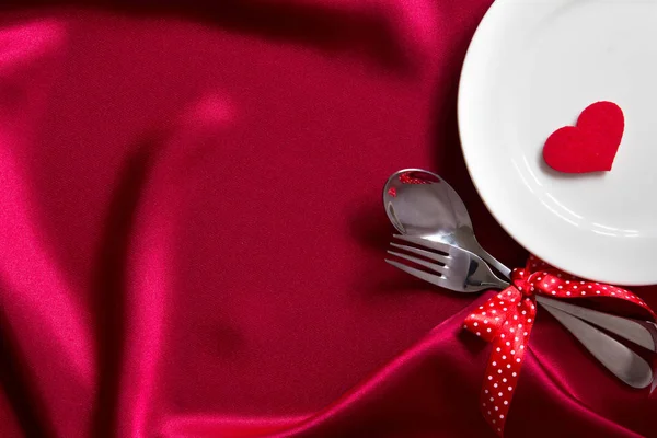 Red heart shape with White empty plate with fork and spoon on re — Stock Photo, Image