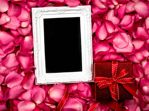 Le cadre photo vide avec pétales de roses roses douces et cadeau rouge — Photo