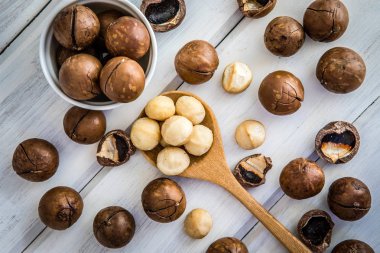 Macadamia fıstığı Beyaz ahşap zemin, superfood ve sağlıklı gıda kavramı, ek yükü veya üst görünüm vintage renk tonu ile vurdu kadar kapatın