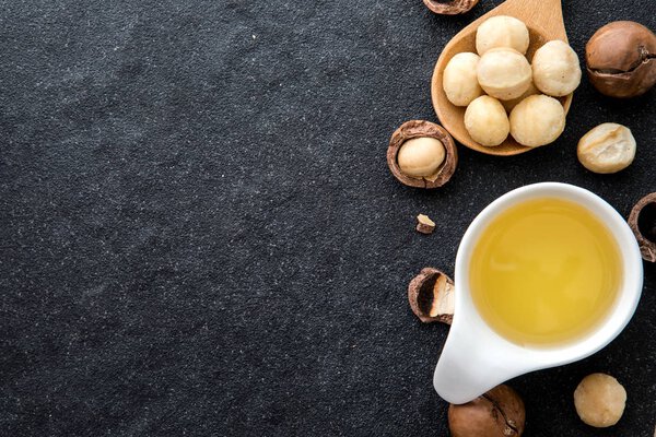  Macadamia Nut Oil and peeled macadamia nut  on black stone , use for Healthy Skin and Hair and Natural Healing Oil Treatment  overhead and top view