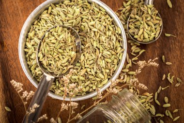 Kahverengi ahşap masada kaşık içine rezene tohumunu kapat.