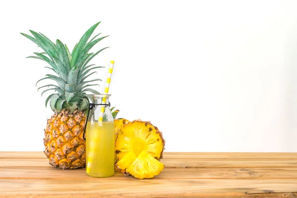 Bottiglie di succo di ananas con frutta a fette di ananas su legno — Foto Stock