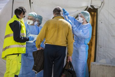 Covid-19 'u uyarın. İlk AID için triyaj hastanesi çadırı, Corona Virüsü bulaşmış hastalar için mobil bir tıbbi birim. Koruyucu maskeli doktorlar girişteki hastaları kontrol edin..