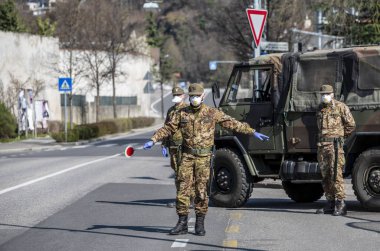 Askerler kontrol eder. Maskeli ve eldivenli güvenlik devriyesi geçen sürücüleri izliyor. Covid-19 küresel krizi için günlük sokak kontrolü. Ordu iş başında..