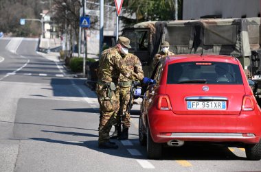 Bozen, İtalya - 14 Mayıs 2020. Askerler kontrol eder. Maskeli ve eldivenli güvenlik devriyesi geçen sürücüleri izliyor. Covid-19 küresel krizi için günlük sokak kontrolü. Ordu iş başında..