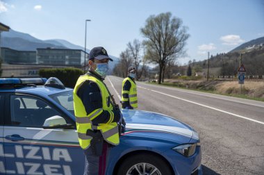 Bozen, İtalya - 23 Nisan, 2020. İtalyan polisi yolu kontrol ediyor. Maskeli ve eldivenli memurlar geçen sürücüleri izliyor. Covid-19 için bir kadın polisle sokak kontrolü. Polis kontrol noktası.