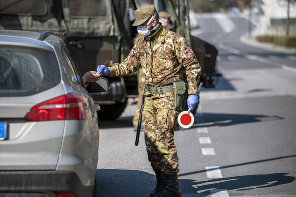 Military soldier controls. Security patrol with masks and gloves monitor passing motorists. Daily street control for the Covid-19 global crisis. The army at work.