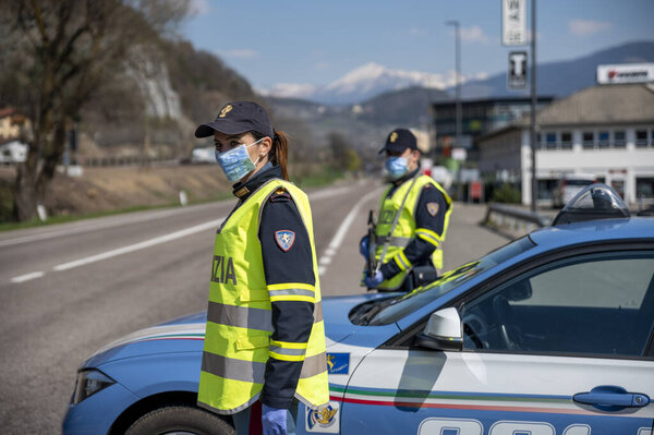 BOZEN, ITALY - APRIL 23, 2020. Italian Police controls on the road. Officers with masks and gloves monitor passing motorists. Street control for the Covid-19 with a policewoman. Police checkpoint.