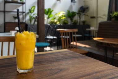 Sağlıklı mango frappe smoothie pipet ve kaşık kafede.