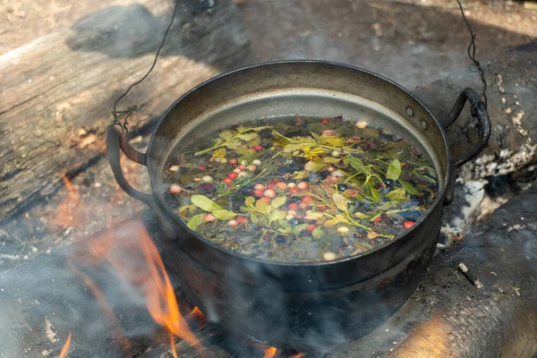 A pot with a herbal tea with berries collected in the forest on campfire