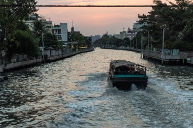 Köprüden Bangkok kanallarına bir yolcu botu ve bir sürü kabloyla bakın.
