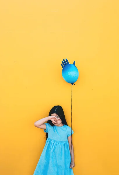 A sad girl holds an inflated glove in her hand instead of a balloon, it is her birthday during the coronovirus pandemic