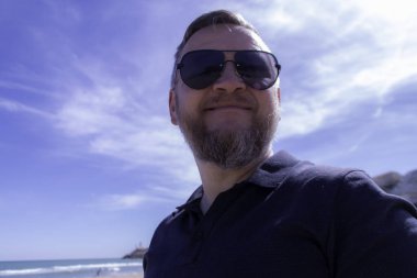 Yetişkin bir adam denize bakıyor.