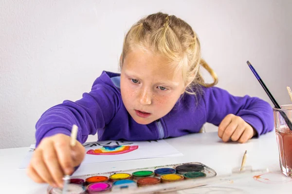 Girl draws a rainbow of hope with the words stay home