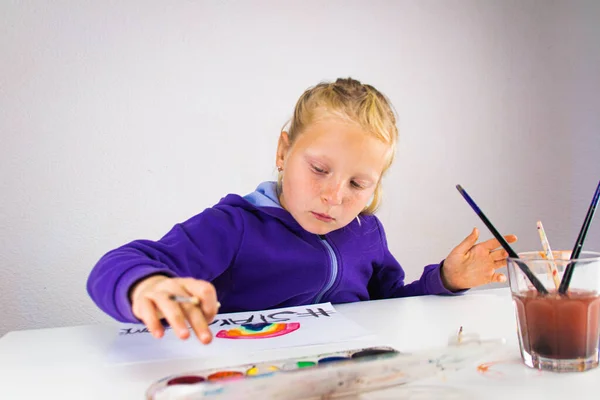 Girl draws a rainbow of hope with the words stay home