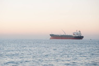 Kargo denizde. Günbatımı arka planında kargo gemisi.