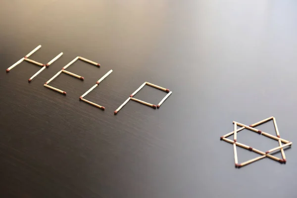 Help with magen David, Israel word from matches. Word help magen David, Israel from matches on black wood. Concept of matches, the inscription Help with magen David, Israel.